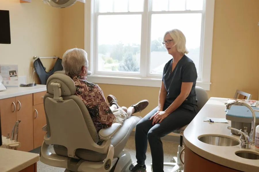 A patient speaking with a Grandville Dental clinician beside the treatment chair