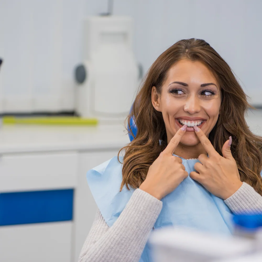 woman pointing at her smile in dentist chair