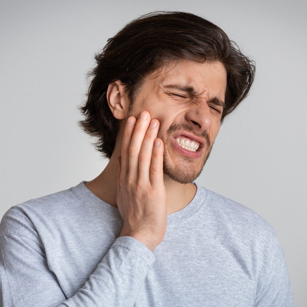 Man grabbing his cheek due to tooth pain